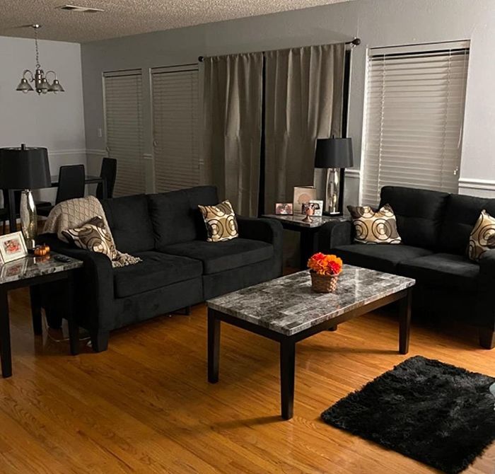 Reviewer photo of a black loveseat and sofa, both with pillows, arranged around a black and gray coffee table