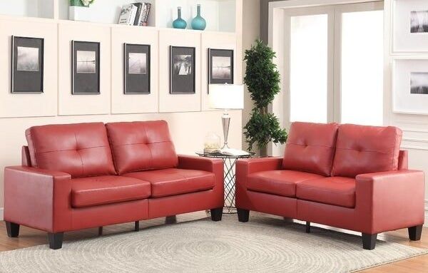 Two red sofas surrounding a beige swirl-patterned rug