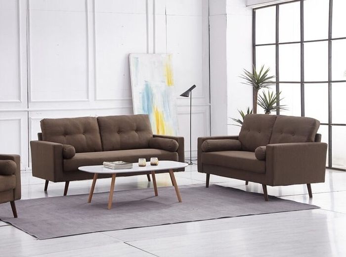 Two dark brown couches next to a chair and a white coffee table