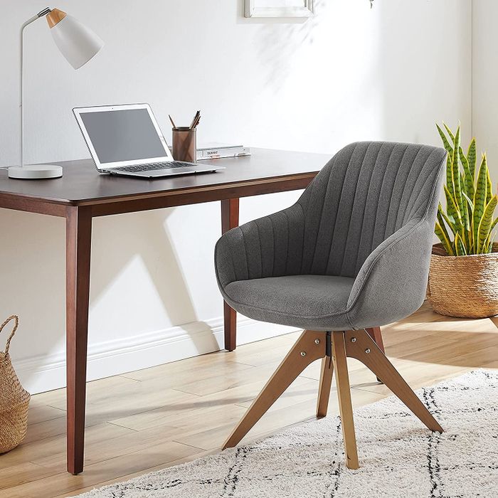 The gray version of the chair positioned in front of a desk, blending seamlessly with the workspace.