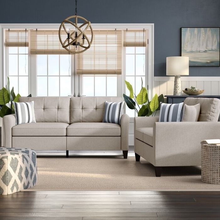 Two light beige sofas surrounding a soft brown rug with a matching patterned ottoman