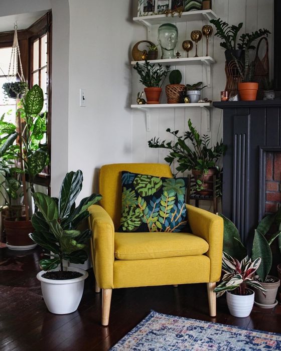 A cozy nook in the living room featuring a bright yellow armchair, surrounded by lush green plants and a beautifully patterned rug.