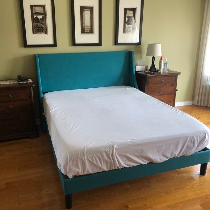 A reviewer’s photo showcasing a turquoise low-profile upholstered bed that adds a modern touch to the bedroom.