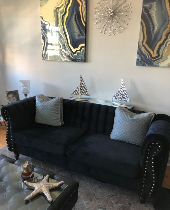 A reviewer image showing a navy blue velvet couch with gray throw pillows positioned behind a coffee table