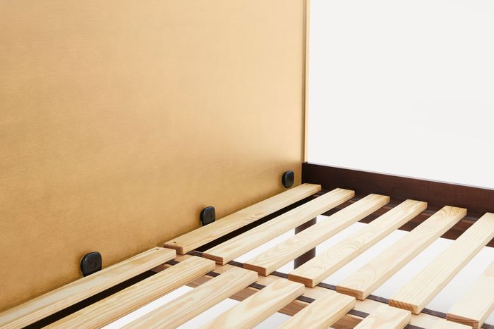 A close-up view of the bed slats and hand screws securely connecting the headboard.