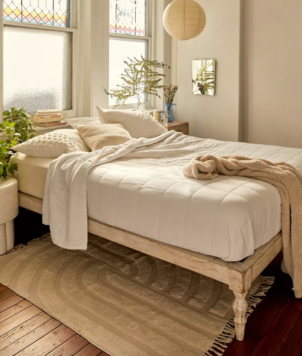 A cozy, bohemian-inspired bedroom showcasing a wooden platform bed with a relaxed, unfinished look, making it the perfect setting for unwinding.