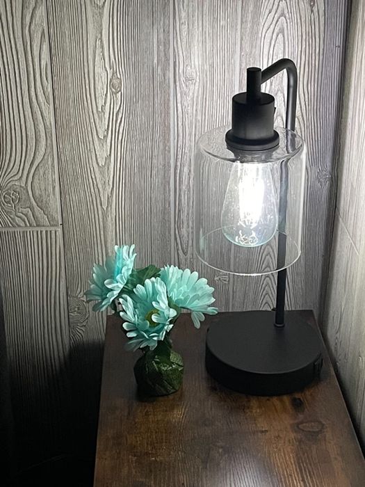 A lamp placed on a nightstand, adding a soft glow to the room.
