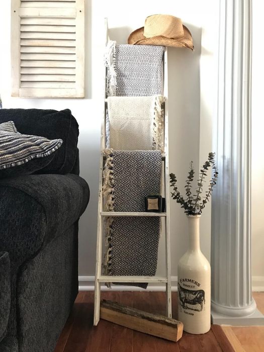 A ladder leaning against the wall, with a blanket draped over each rung in a cozy living room.