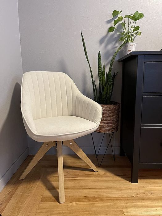 A photo from a reviewer showcasing the white chair placed in the corner of a bedroom, adding a touch of style to the space.