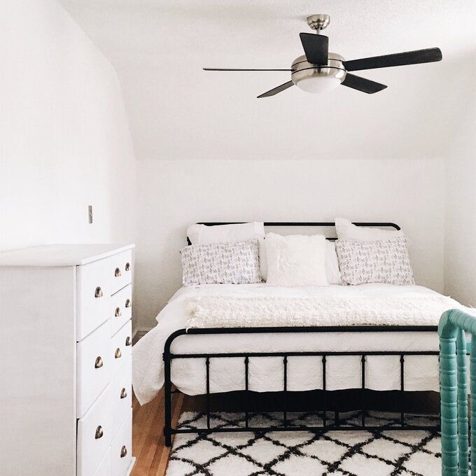 A photo from a reviewer showcasing a metal platform bed placed in a sleek all-white bedroom setting.