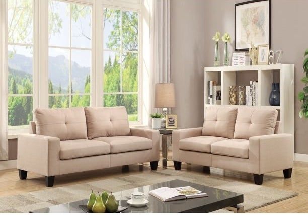Beige sofas arranged in front of a brown carpet and a black coffee table