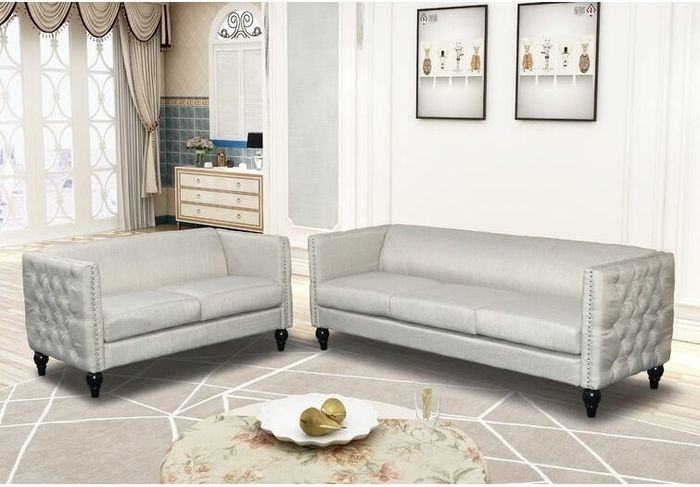 Two beige couches on a brown abstract rug beside a floral coffee table