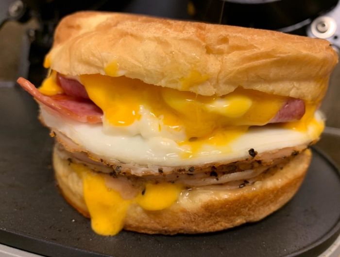 Close-up image of a sandwich with melted cheese, ham, and a fried egg