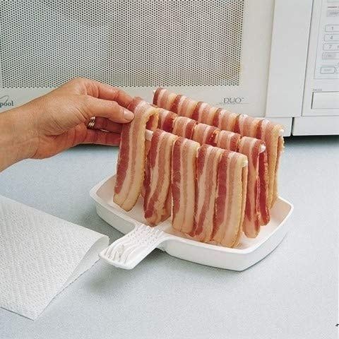 Raw bacon strips hanging neatly on the cooker.