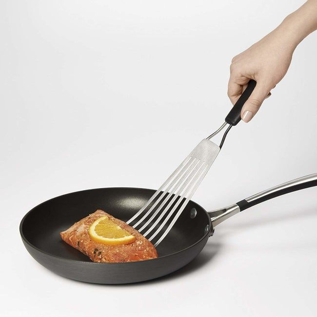 The fish turner holding a salmon filet in a frying pan