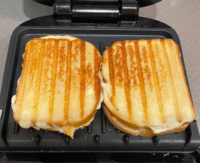 Two grilled cheese sandwiches being made on an electric sandwich press