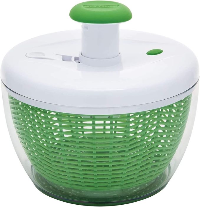A salad spinner with a clear bowl and a green inner basket, featuring a convenient push button on top for easy operation.