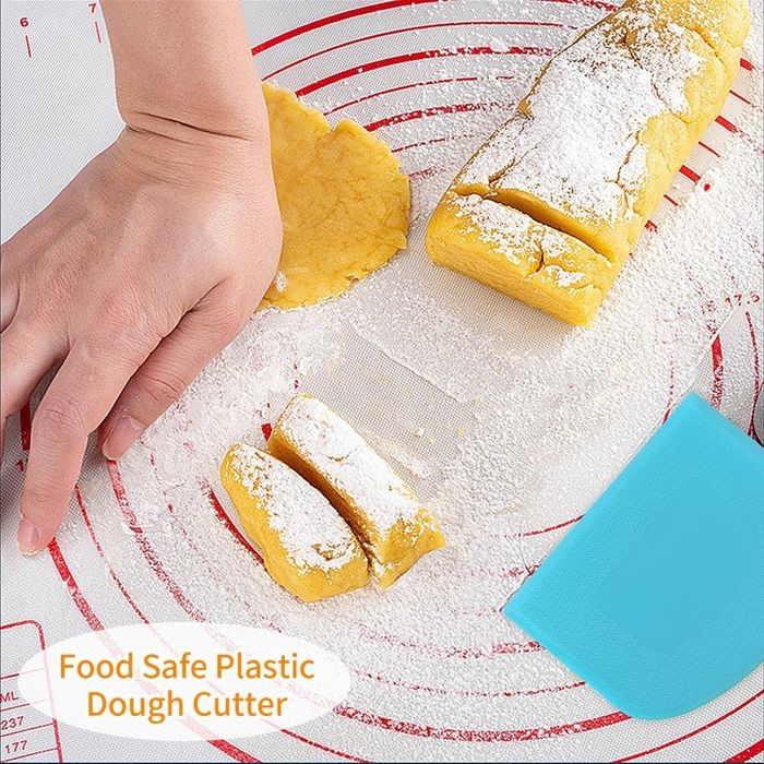 A hand using a plastic dough scraper to cut rolled dough on a non-stick baking mat dusted with flour. Text reads: