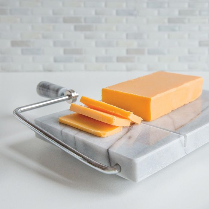 Slices of cheddar cheese resting on a marble board