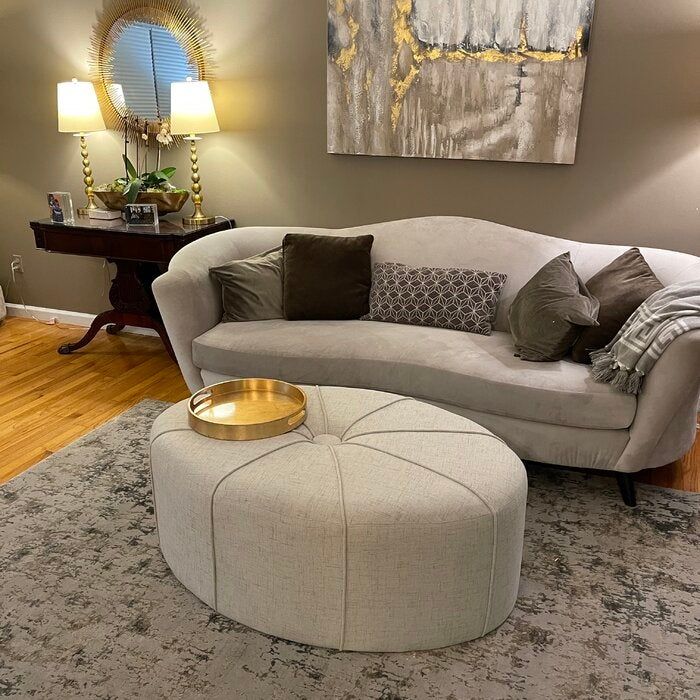 A reviewer's photo of an ivory oval ottoman coffee table