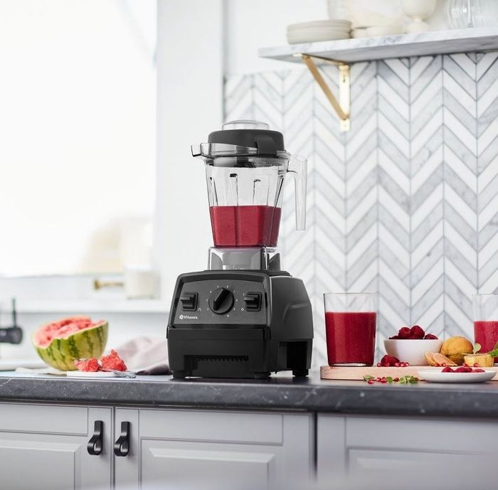 A black Vitamix blender with a fuchsia-colored smoothie inside.