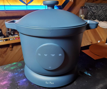 A matte blue electric cooker featuring a digital control panel for precise settings.
