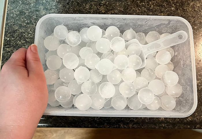 A reviewer's container filled with ice spheres and a scoop