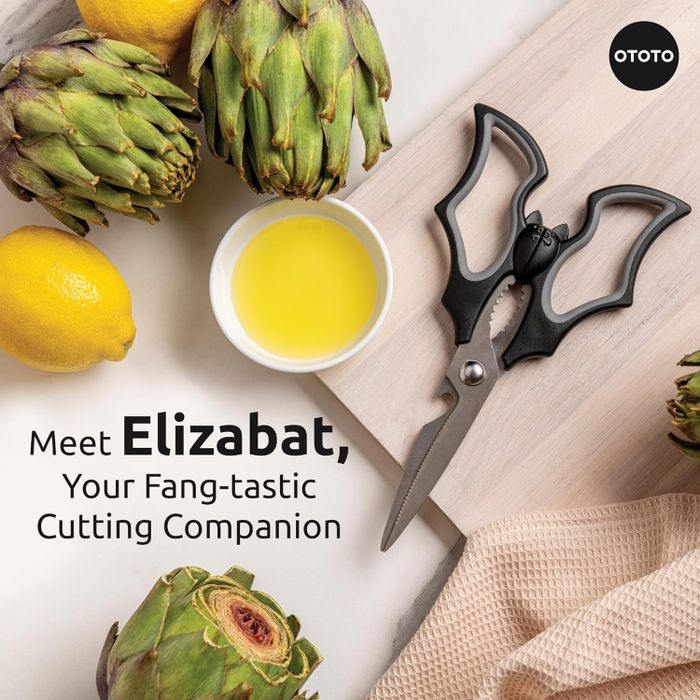 Advertisement for Elizabat scissors, designed like a bat, accompanied by artichokes, a lemon, and olive oil.