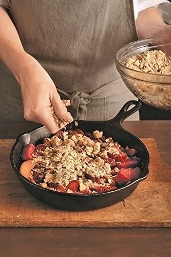 A model sprinkling crumbs over a freshly baked dish in a cast-iron skillet.