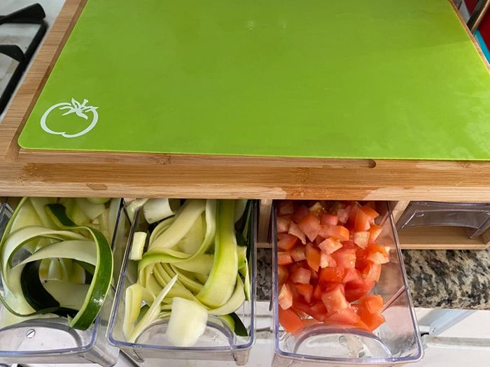 A cutting board with pull-out containers designed for holding sliced vegetables