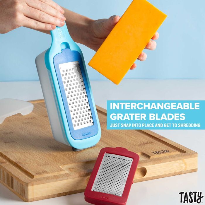 A cheese grater with interchangeable blades, placed on a wooden cutting board, with a block of cheese ready to be grated.
