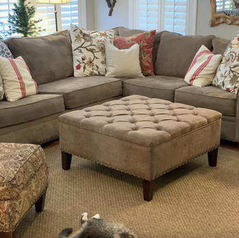 A photo review showcasing a brown faux leather large square ottoman with four legs.
