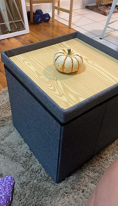 A photo review featuring a cube storage ottoman with a pumpkin placed on top of it.