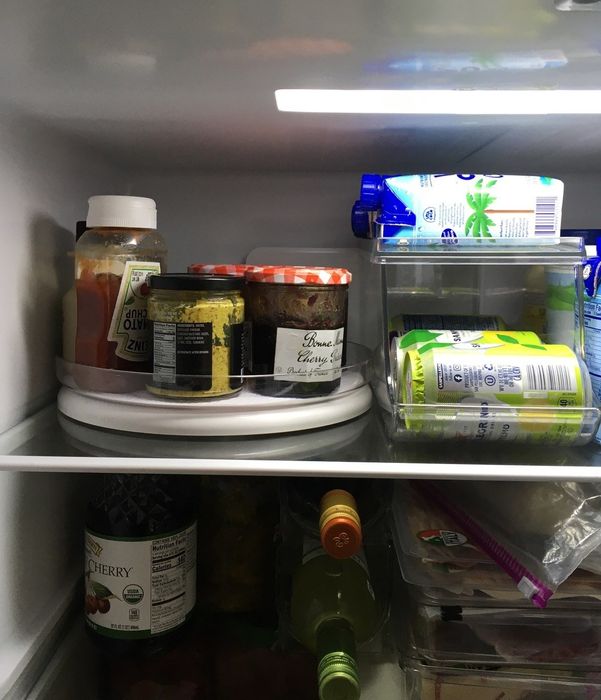 The turntable holding a variety of condiments on the top shelf of a fridge