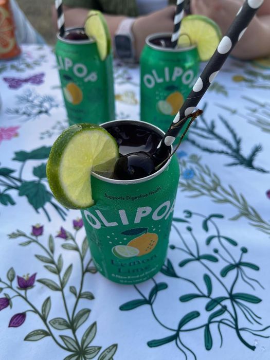 Topless Olipop lemon-lime soda cans, each with a straw and slices of lime for added zest.