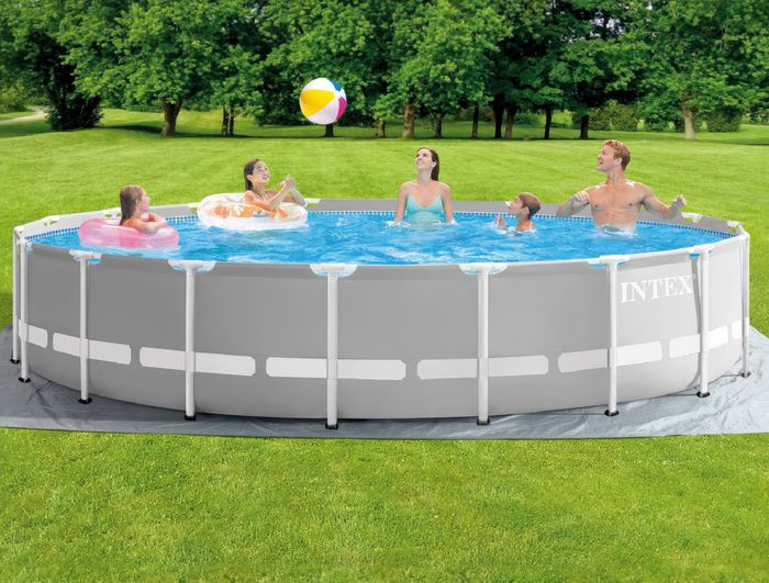 A group of people having a great time, swimming in an above-ground pool set up on a lush, grassy lawn.