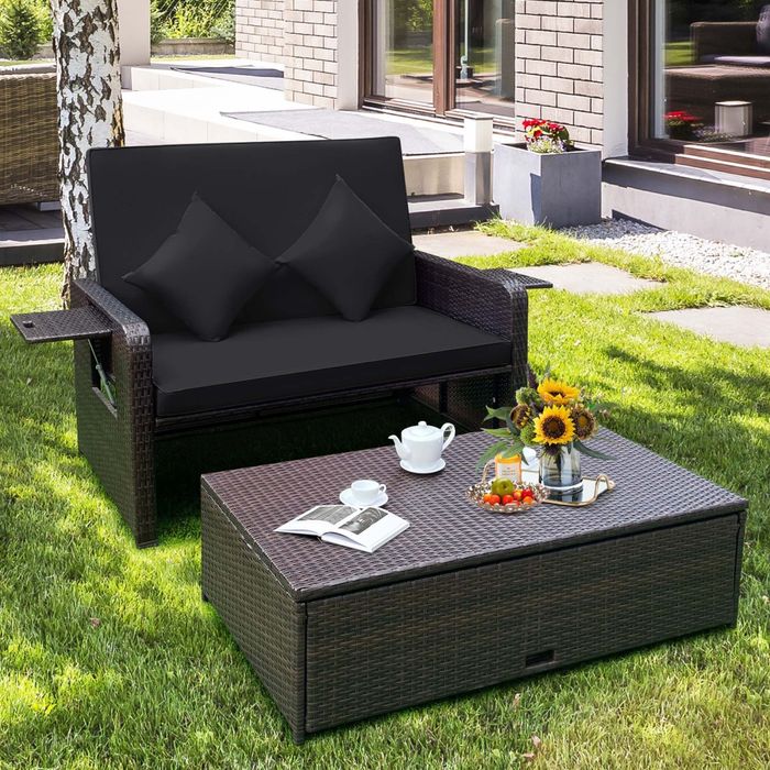 The black daybed in its upright position with the side tables extended and the ottoman serving as a coffee table.