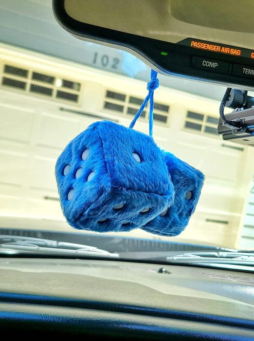 A reviewer’s blue fuzzy dice hanging from their rearview mirror