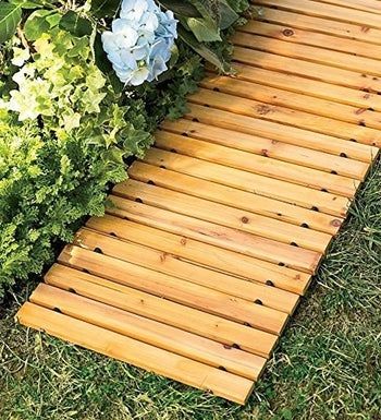 A slotted wooden pathway alongside a bed of hydrangeas
