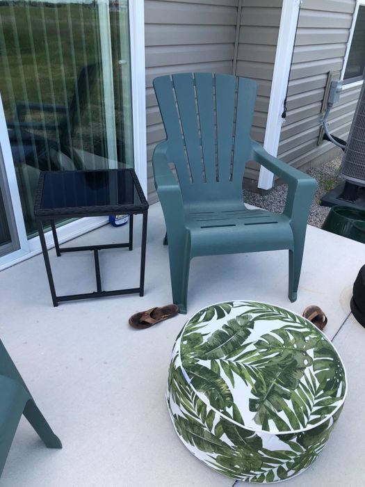 A reviewer's photo showing a patio chair with a palm-printed inflatable ottoman placed in front of it