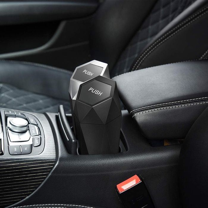 A mini trash can placed inside a car cup holder