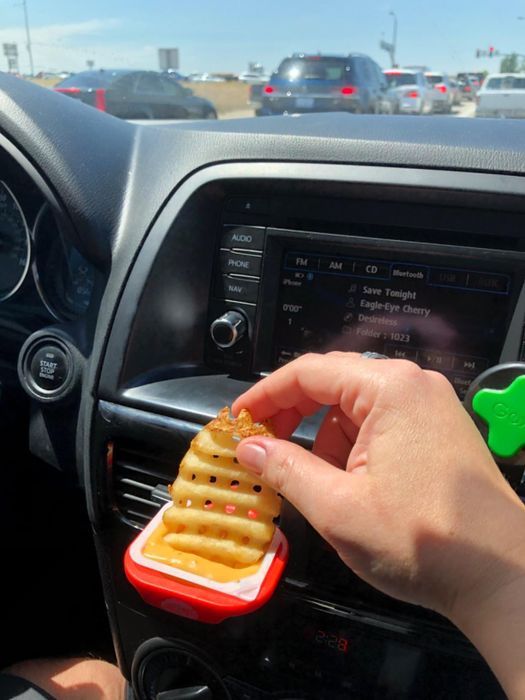 reviewer dipping a fry into the sauce held by the dip clip