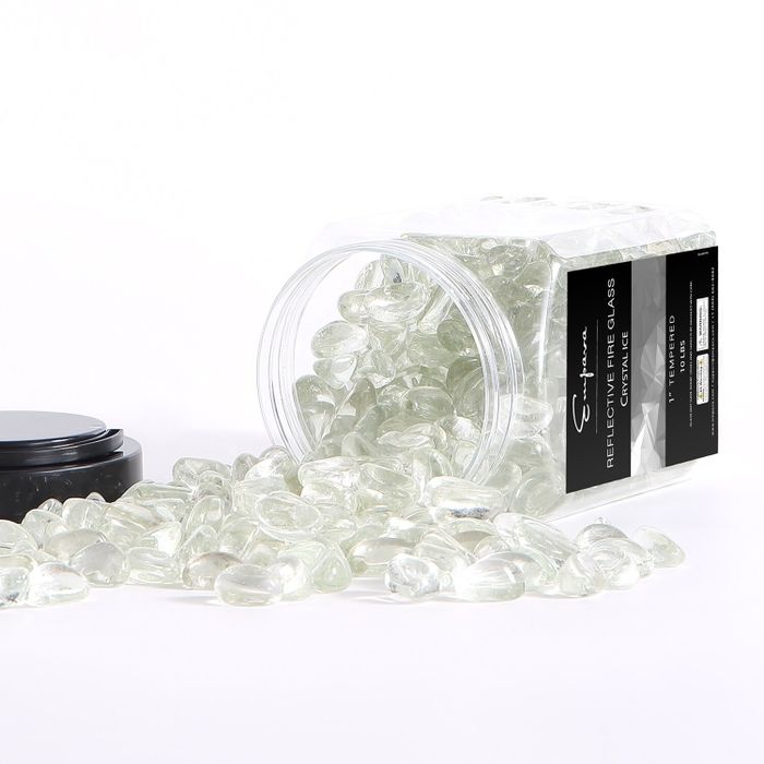 A clear plastic container of Signature Reflective Fire Glass Chunks rests on its side, with shimmering, transparent glass pieces spilling out around it.