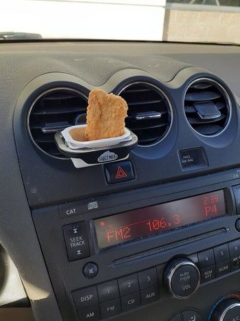 The dip clip attached to a reviewer’s car air vent with sauce and a nugget in it