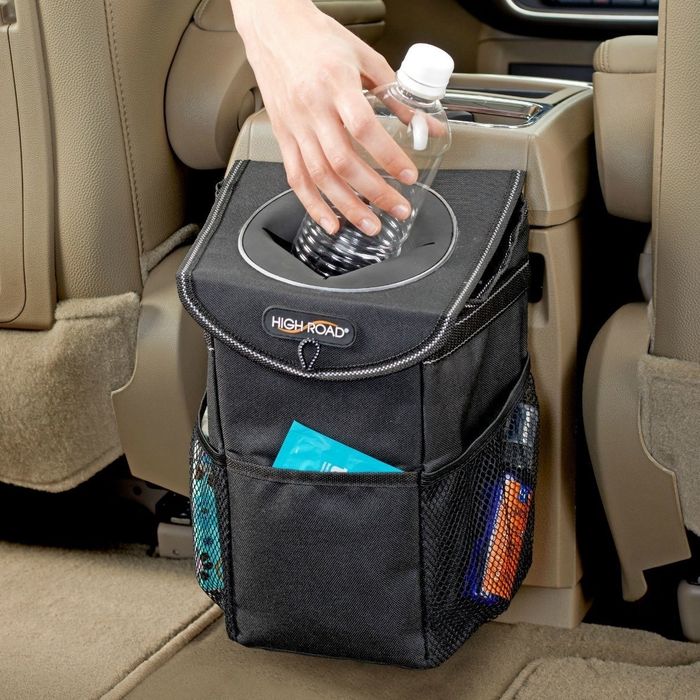 A model placing an empty water bottle into the trash can attached in a car