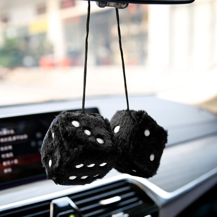 Black fuzzy dice swinging from a car’s rearview mirror