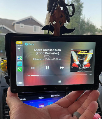 reviewer holding their touch screen displaying music playing on the screen