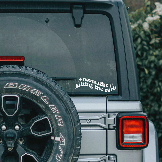 Back of a vehicle with a spare tire, showcasing a bumper sticker that reads