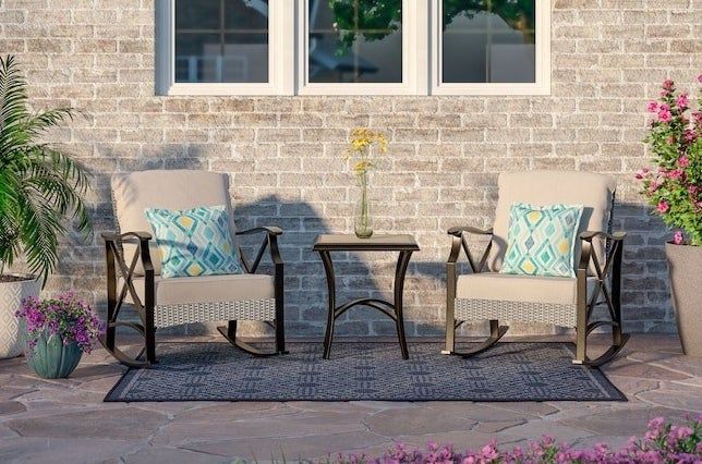 A patio ensemble featuring two cushioned rocking chairs and a coordinating table, perfect for outdoor relaxation.