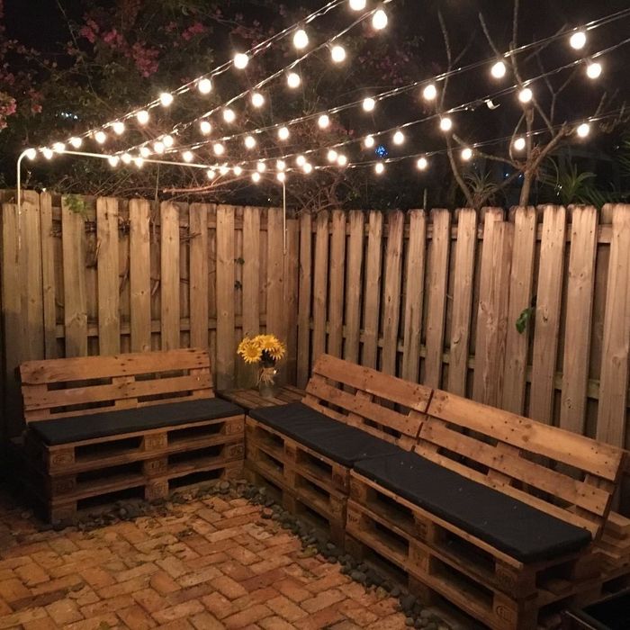 A reviewer’s photo showing a backyard with strings of lights hanging above a set of benches
